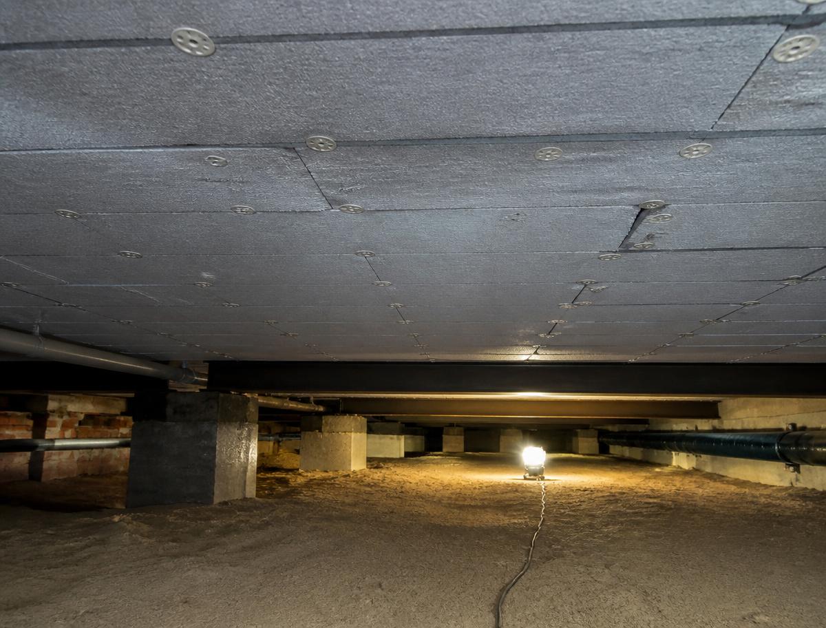 Isolatieplaten worden onder de begane grondvloer bevestigd in de kruipruimte